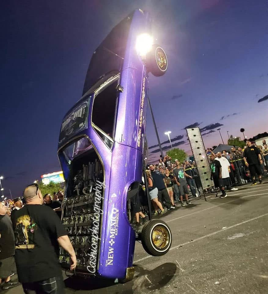 Purple lowrider on hydraulics standing vertical at night event